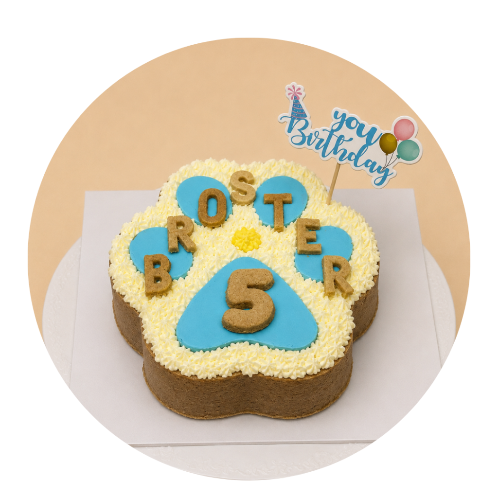 Torta en forma de huella de perro color blanca con decoraciones en celeste y amarillo y el nombre "broster" hecho en galletitas para perros